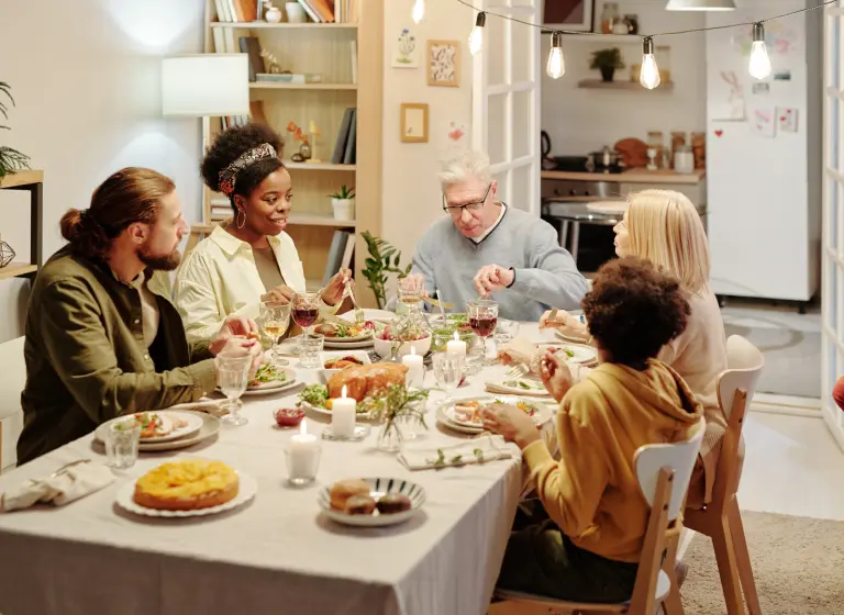 A racially diverse multi-generational family are enjoying a meal together inside at home.