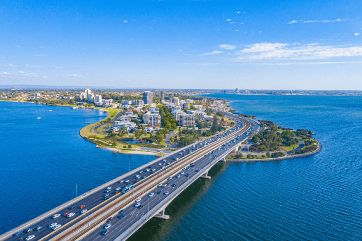 An image of a bridge over a body of water connecting to a city and buildings