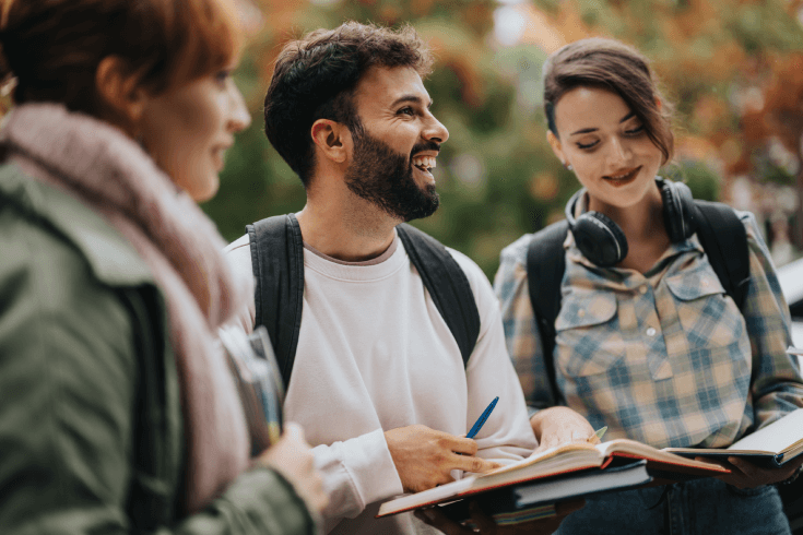 Group of three students outside with notebooks open