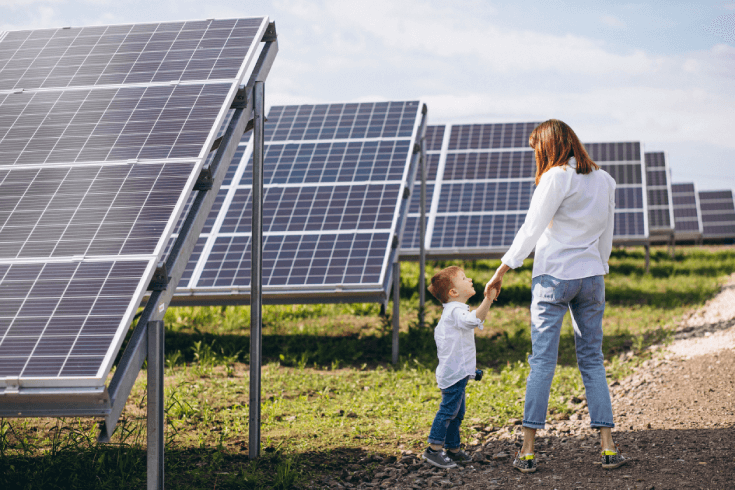 Mother with her young son in front of rows of solar panels.