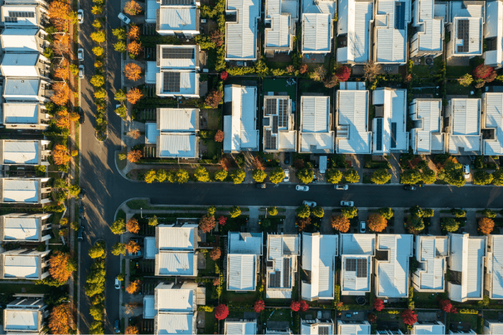 Aerial view of suburban home area. T-shaped street with solar panels homes and tree lined streets.