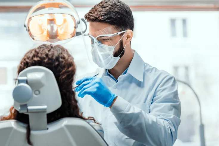 A male dentist performs a dental check-up on a female patient.