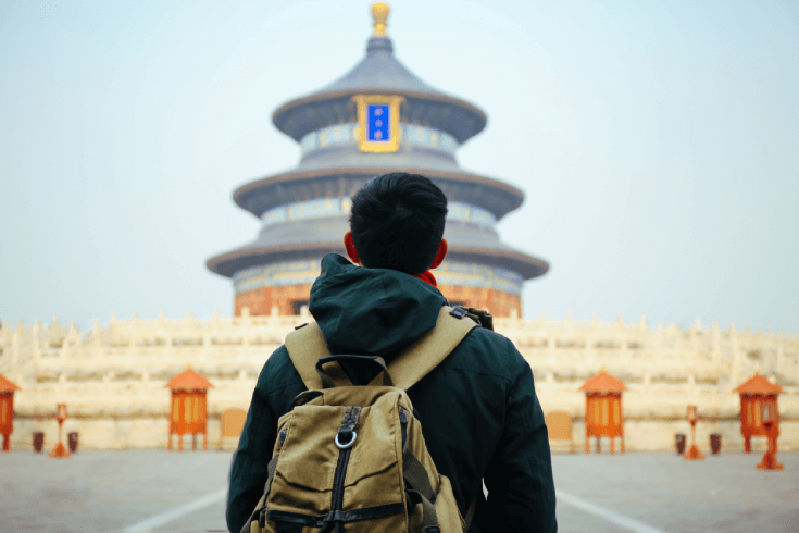 Young traveller’s back with backpack standing in front of the Temple of Heaven in Beijing, China.