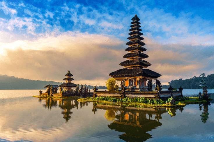Pura Ulun Dana Bratan temple in Bali. Multi-tiered temple sitting on open water with hills in the background.
