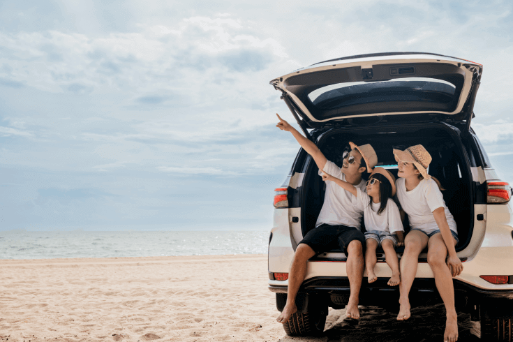 Family sitting in car boot at the beach