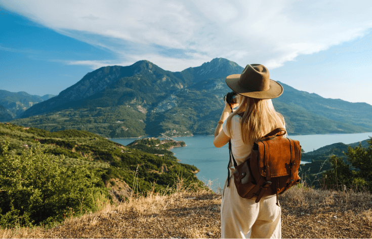 Woman taking photo of mountain and lake.