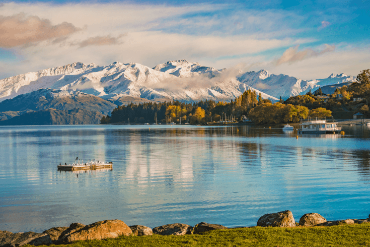 Queenstown Lake with snow-capped mountain range and forest in background.