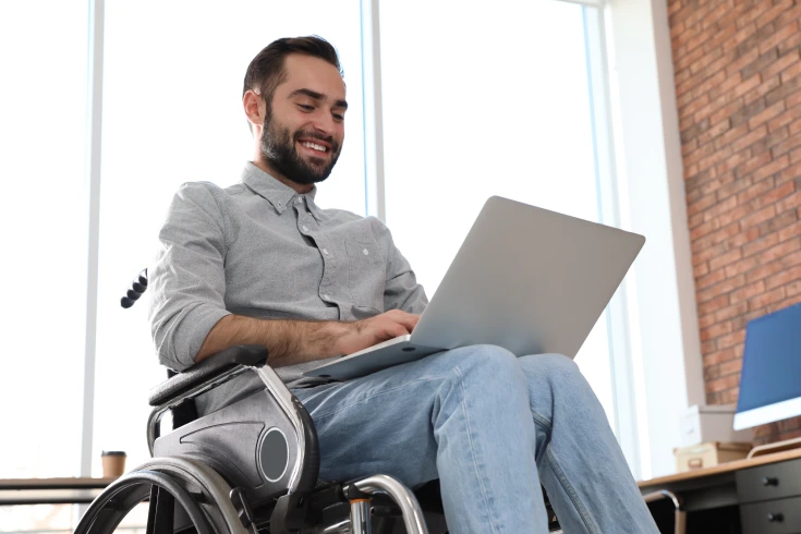 A man in a wheelchair uses a laptop to check the status of his income protection payout