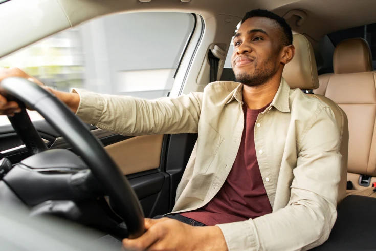 An image of a person looking relaxed and driving a car