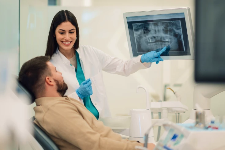 A patient eligible for Medicare dental care views an X-ray of their teeth as a dentist explains treatment options