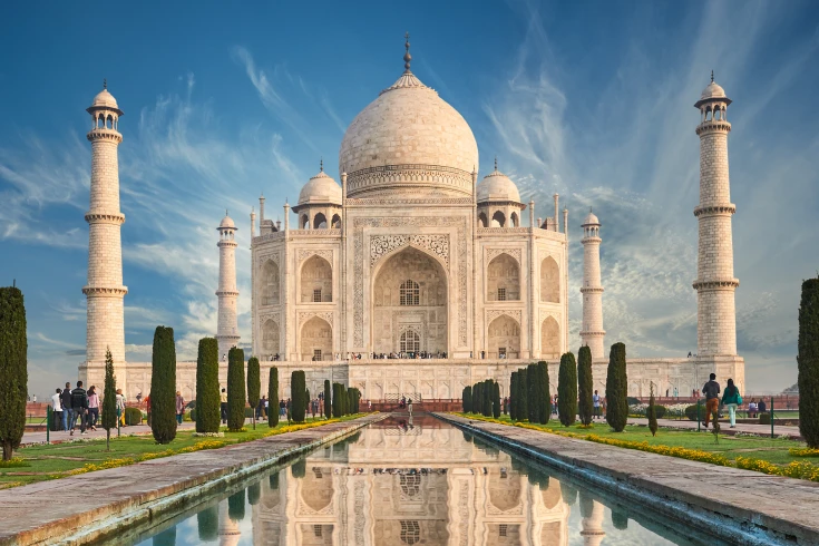 View of the Taj Mahal with blue sky and a long waterway in front
