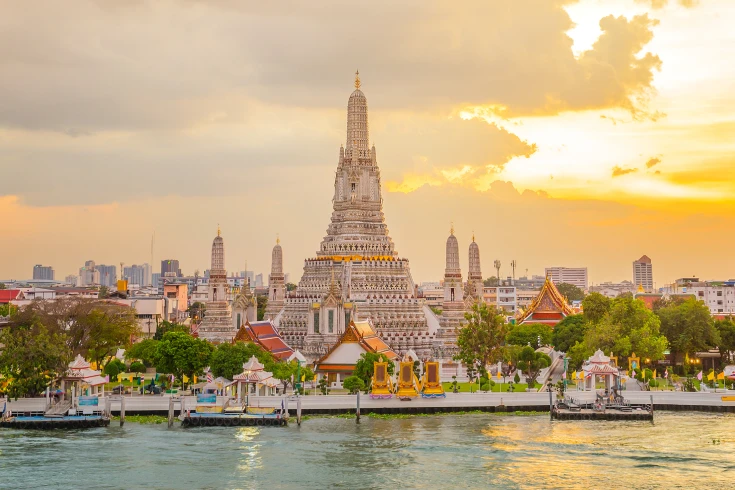 Sunset view of a Thailand temple with water front and city in background