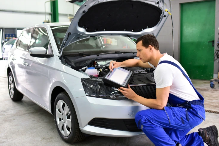 A mechanic looks under the hood of a car