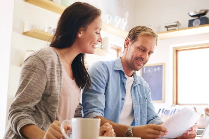 Man and woman in kitchen reading paper bill together
