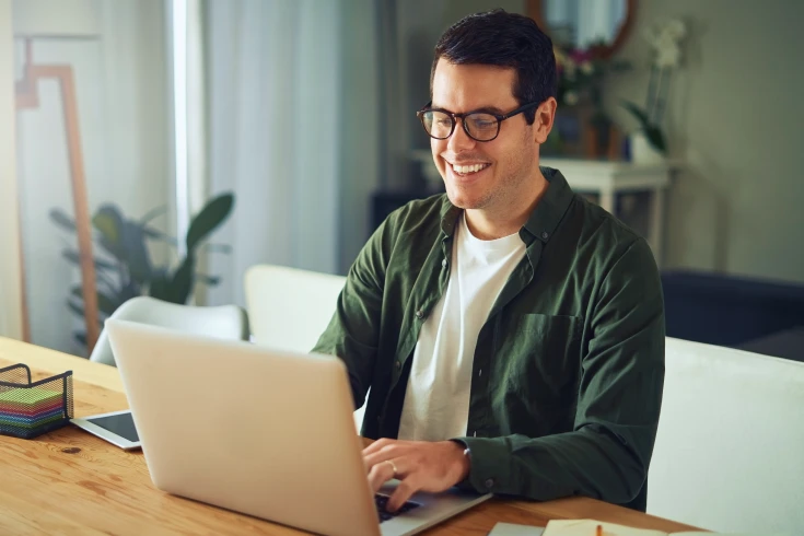 A man sits in his living room and types on his laptop