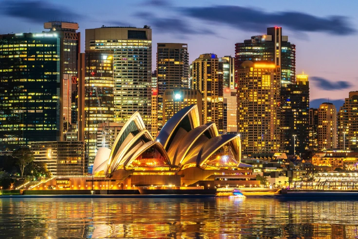 Sydney Opera House illuminated at dusk with city skyscrapers in the background for a gas connection page