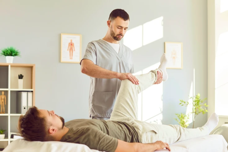 A physiotherapist checks a patient’s knee’s range of movement after surgery