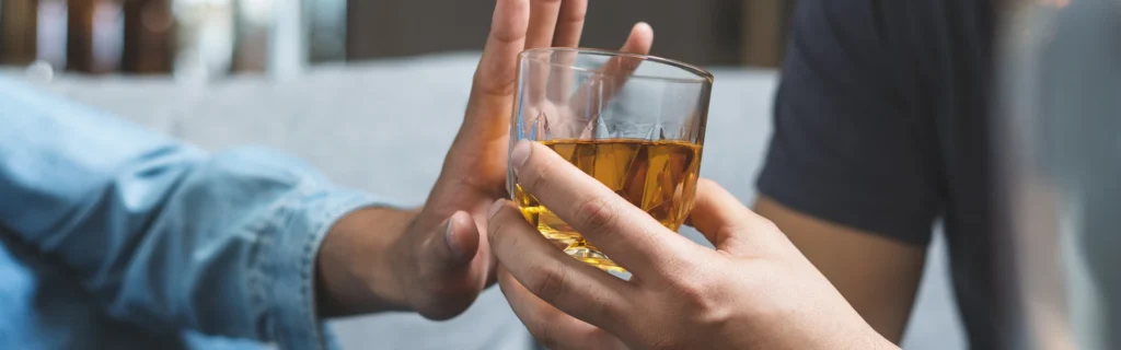 A picture of someone denying the offer to have an alcoholic beverage. The beverage looks like a scotch/whiskey.