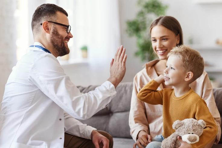 A doctor gives a child a high five during an appointment