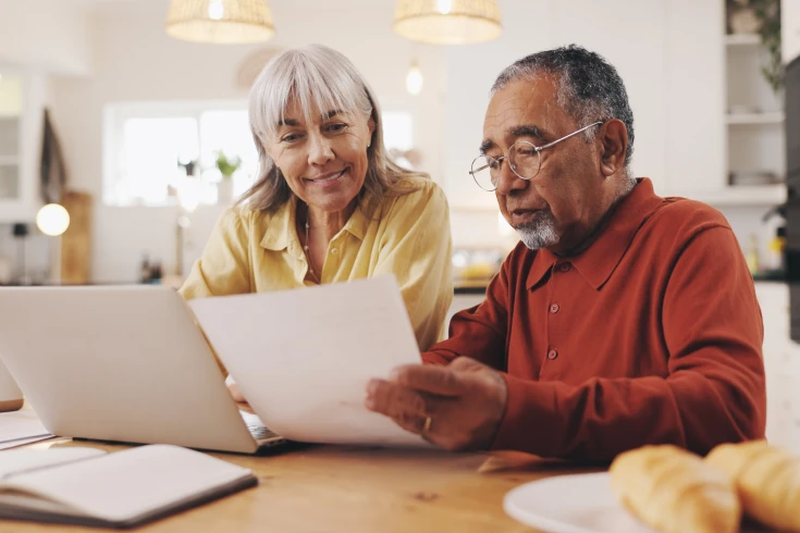 Couple looking at paperwork while in front of a laptop to see how much their premium rate has changed