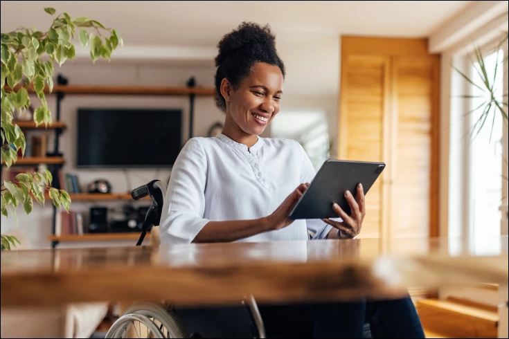 Woman sitting at a table looking at a tablet