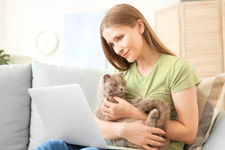 Pet owner cuddling her cat while looking into her pet insurance policy’s waiting periods
