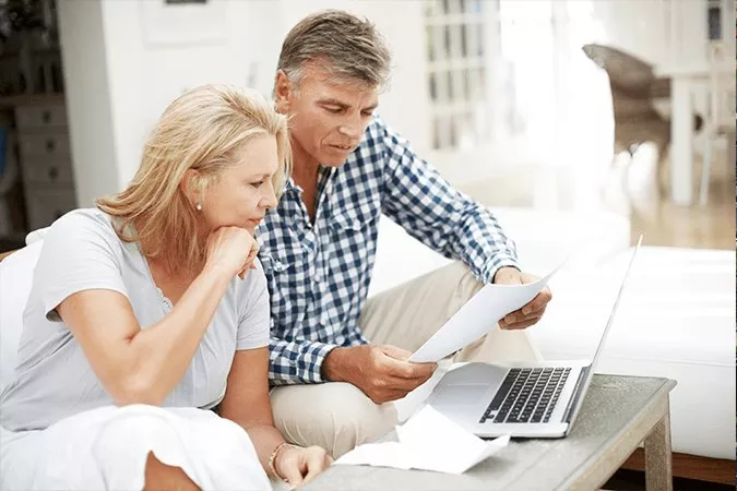 A couple go through their health care invoices and make related health insurance claims online