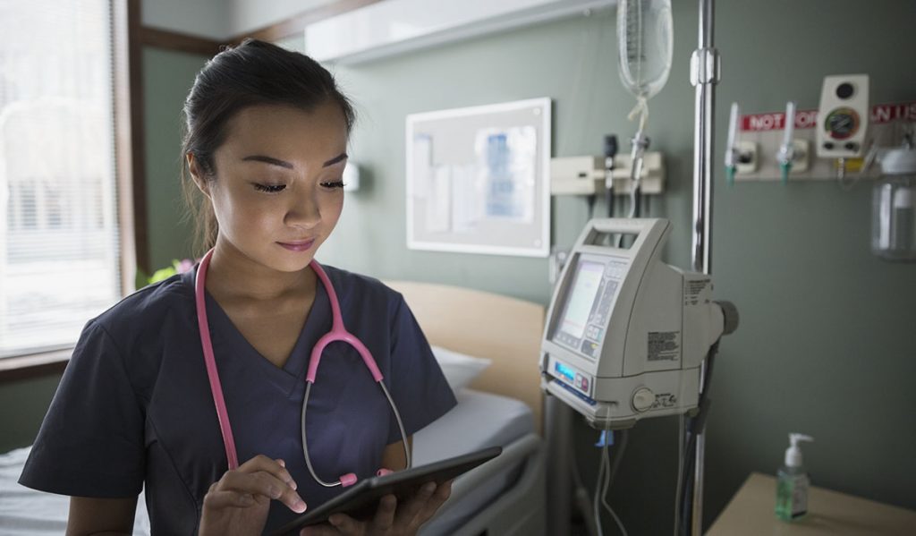 A doctor reviews the medical information of a patient in hospital using a digital tablet