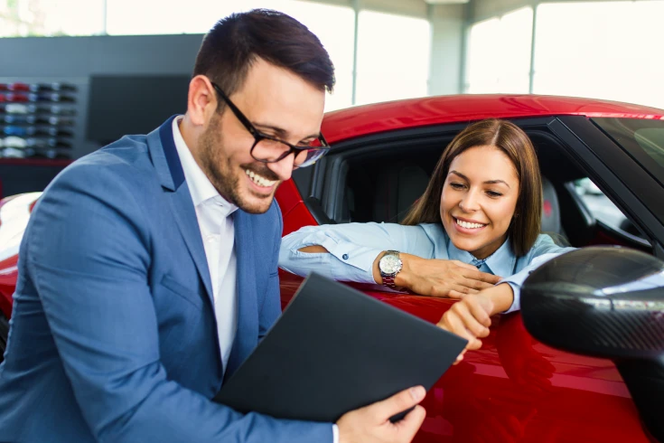 An image of a man showing a document to a woman sitting in a car