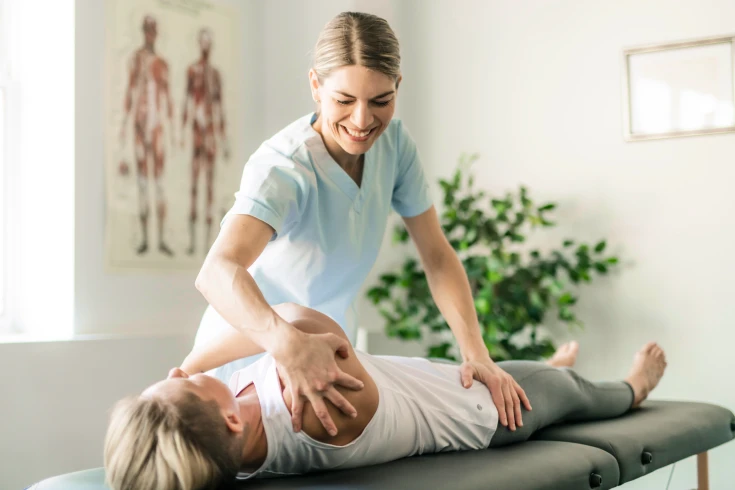 A remedial massage therapist applies pressure to a patient’s shoulders and legs to help joint mobility