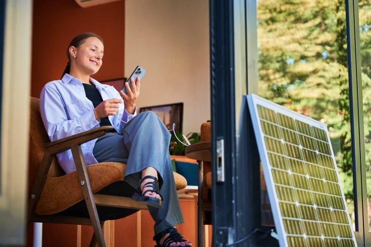 Woman sitting on a chair with a solar panel sitting outside against the door