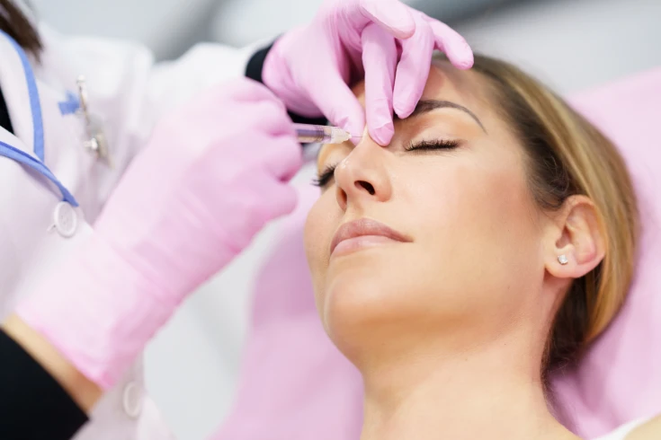 A surgeon examines a patient's nose ahead of a rhinoplasty