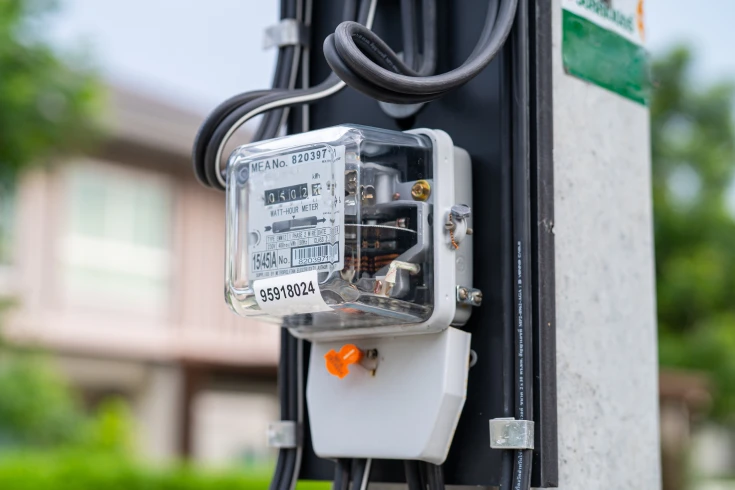 Electricity meter on a power pole with a house in the background