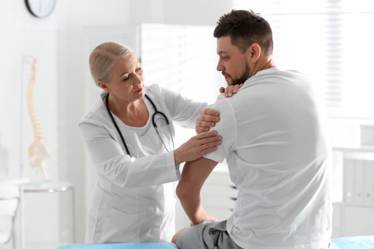 Male patient having his shoulder checked for a potential surgery in a doctor’s clinic