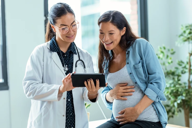 Pregnant woman with a doctor looking at the cost of giving birth